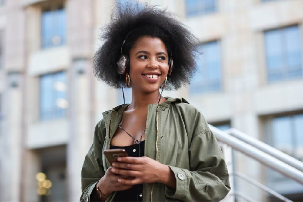Tech Essentials for travel African women wearing headphones while smiling at road