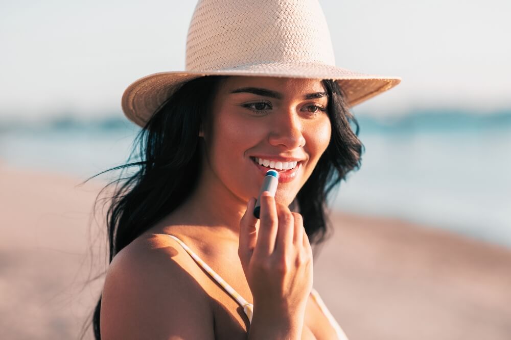 Beach Vacation Packing Tips Women smiling and applying spf lip blam at beach