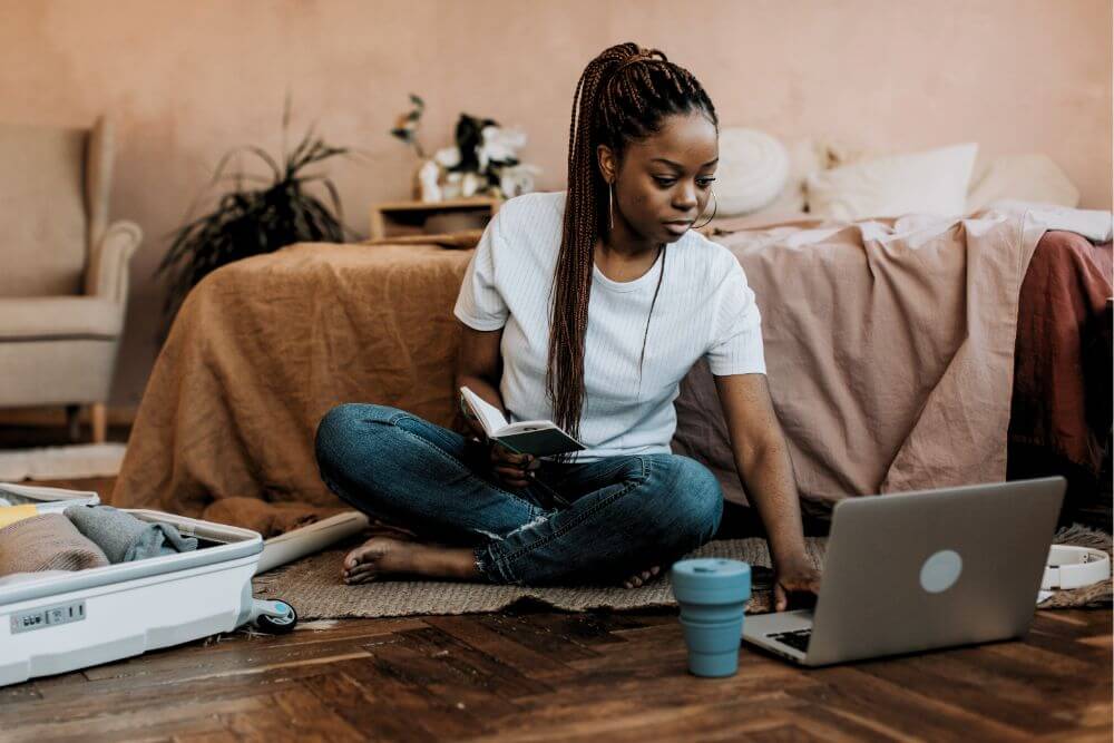 Untitled design (43) woman with long brown braided hair using laptop on floor